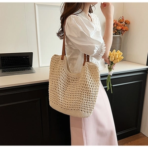 Detailed view of beige straw woven tote bag with brown faux leather shoulder straps