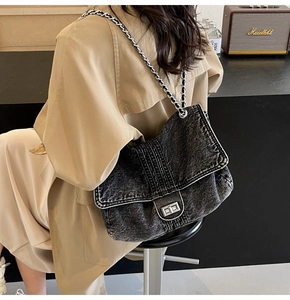 Detail of dark grey washed denim crossbody bag with silver chain and twist lock clasp