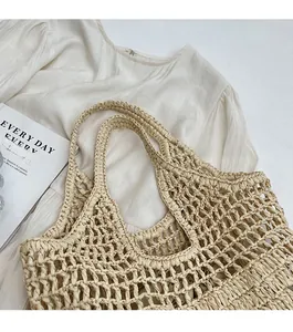 Detailed close-up of handmade off-white woven straw tote bag with intricate hollow crochet