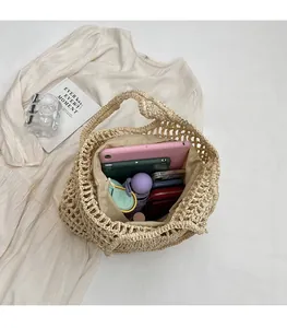 Vue intérieure du sac en paille beige montrant l'espace pour tablette et accessoires