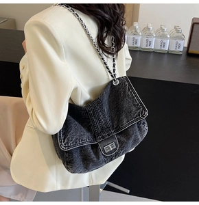 Detailed view of grey denim crossbody bag with metallic chain and square twist lock
