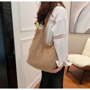Detail of woven straw tote bag with brown leather handles and interior tulip flower accessory