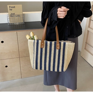 Detail of navy and beige striped woven tote bag with leather handles and silver rivets