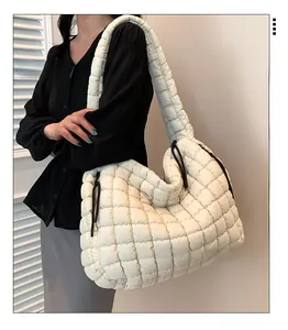 Detailed view of white quilted puffer tote bag with side drawstring worn by a model