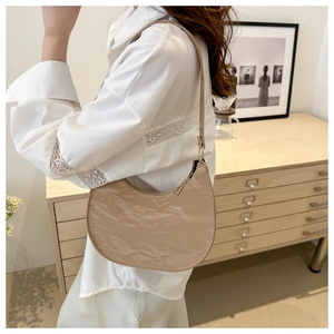 Detail of beige half-moon shoulder bag with pleated faux leather texture and minimalist design