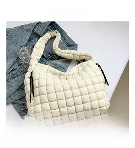 Close-up of cream quilted cloud bag featuring puffer square texture and side knot detail