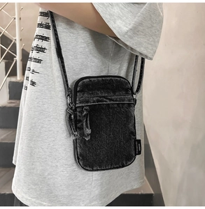 Detailstruktur der schwarzen Denim-Umhängetasche mit Vintage-Waschung und Stoffetikett