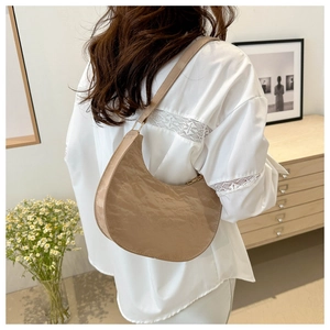 Chic beige hobo bag with pleated texture and gold zipper shown in a lifestyle indoor setting