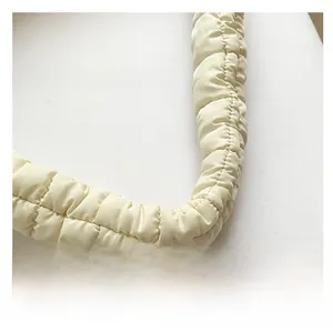 Close-up of padded ruched shoulder strap with quilted texture and soft cream finish