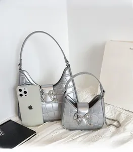 Detail of silver crocodile texture bags with rhinestone bow and metal chain strap