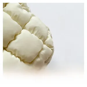 Close-up of cream quilted nylon tote bag with puffy grid texture and side strap detail