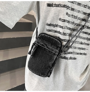 Nahaufnahme der gewaschenen Denim-Handytasche mit minimalistischem Label auf Beton