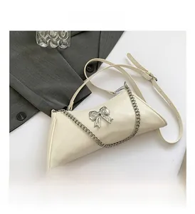 Detail view of cream PU leather shoulder bag featuring silver metal bow and chain strap