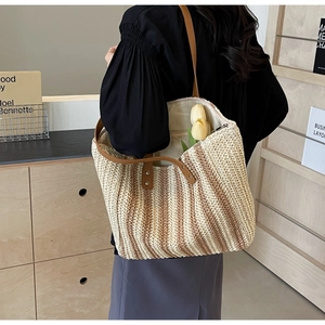 Detail of spacious straw tote bag with brown leather handles and secure zip closure