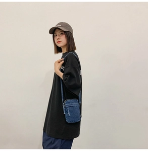 Detail einer dunkelblauen Denim-Mini-Umhängetasche kombiniert mit legerer Streetwear