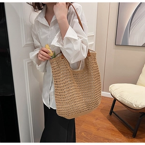 Detail of hand-woven straw tote with premium brown leather straps on a white shirt