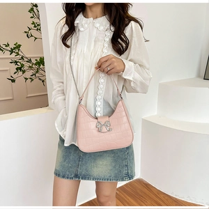 Detail of pink faux leather half-moon bag with crocodile texture and crystal bow