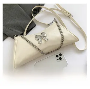 Detail of cream PU leather handbag with silver metallic bow and chain handle in macro view