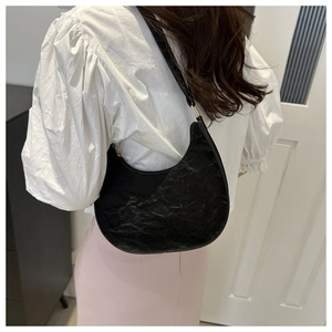 Detail of the black half-moon hobo bag with unique wrinkled texture and glossy PU leather