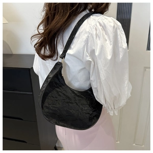 Fashionable black crescent shoulder bag with glossy pleated texture and slim strap design