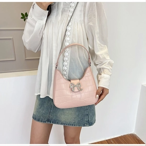 Close-up of pink faux crocodile leather bag with sparkling rhinestone bow buckle and chain