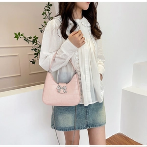 Pink croc-effect underarm bag featuring a sparkling rhinestone bow and chain strap