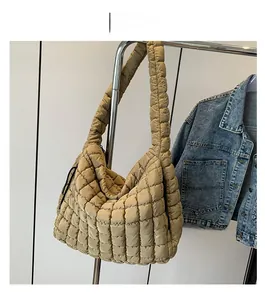 Detail showing the puffy quilted texture and thick shoulder strap of a brown puffer tote bag