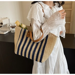 Detailed view of woven tote bag with blue stripes and brown leather straps on model