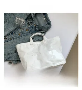 Close-up of white glossy DuPont paper tote bag with embossed text on denim background