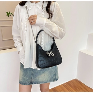 Detail of black crocodile texture bag featuring a sparkling rhinestone bow metal buckle
