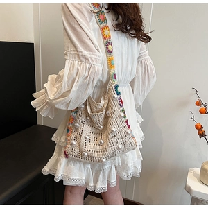 Detail der Boho Häkeltasche mit weißen Perlen und buntem floralem Schultergurt