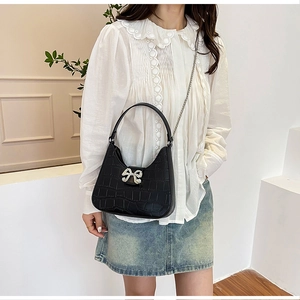 Detail of black crocodile texture bag with crystal bow buckle and chain strap