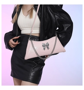 Detail view of pink PU leather crossbody bag with silver bow hardware and chain strap