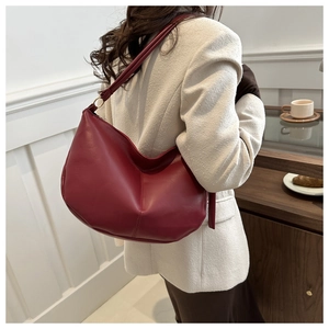 Detail of burgundy PU leather crescent bag with vertical stitching and gold metal ring