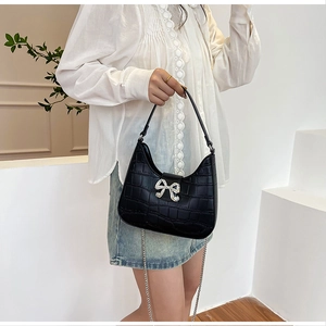 Detail of black faux crocodile leather bag with sparkling silver rhinestone bow accent