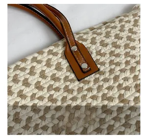 Close-up of woven straw bag with leather handle and reinforced metal rivets