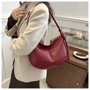 Detail of burgundy PU leather shoulder bag with vintage hobo design and knotted strap
