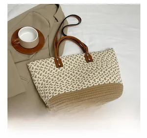 Close-up of woven straw tote bag with brown leather handles and metal rivet details