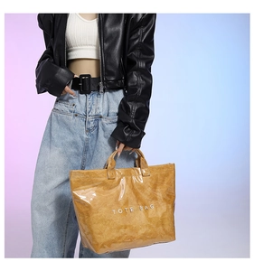 Detail of yellow tyvek tote bag with glossy finish and white printed text on handle