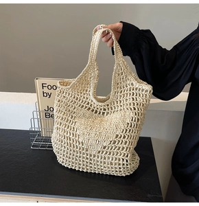 Detail of straw woven tote bag featuring hollow heart pattern and handmade mesh design
