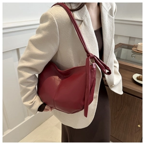 Detail of a dark red PU leather half-moon crossbody bag with a stylish knotted shoulder strap
