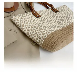Close-up of woven straw handbag featuring brown leather handles and metal rivet details