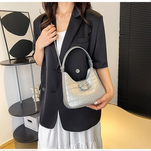 Close-up of silver crocodile pattern PU bag with rhinestone bow buckle and metal chain