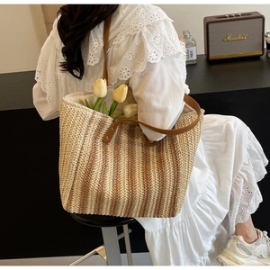 Detail view of woven straw tote bag with brown leather straps and tulip floral decor
