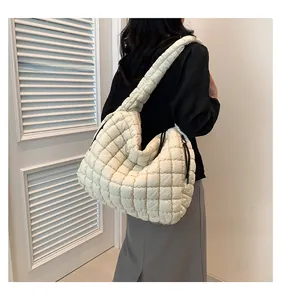 Detailed side view of off-white quilted cloud bag worn as a spacious shoulder tote bag