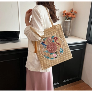Detailed close-up of woven tote bag featuring traditional Chinese embroidery and silk tassel