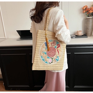 Detail of straw tote bag with traditional dragon embroidery and gold silk tassel