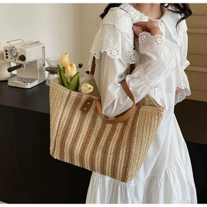 Close-up of a large striped straw tote bag showing interior space and brown leather handles