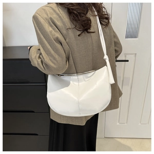 Close-up of a white PU leather crescent bag featuring a unique knotted shoulder strap