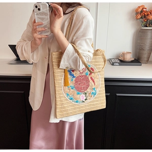 Detail of beige straw tote bag with traditional Chinese red embroidery and tassel